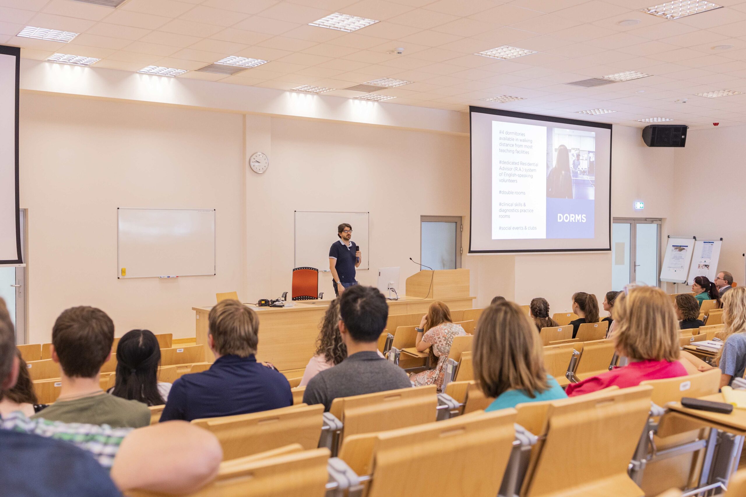 A man gives a presentation in front of a large audience, illustrating his ideas and engaging the audience.