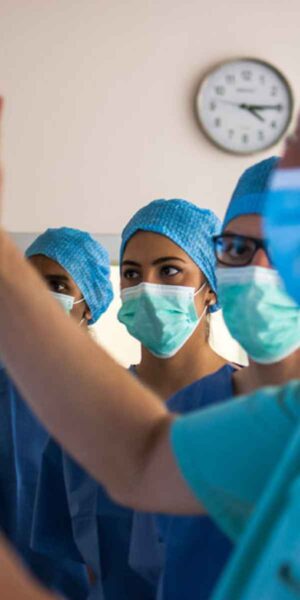 A team of surgeons wearing scrubs and masks collaborates in a sterile operating room environment.