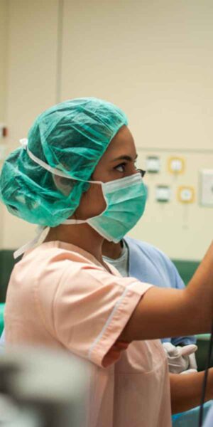 A focused nurse in an operating room prepares medical instruments, contributing to a safe and efficient surgical environment.