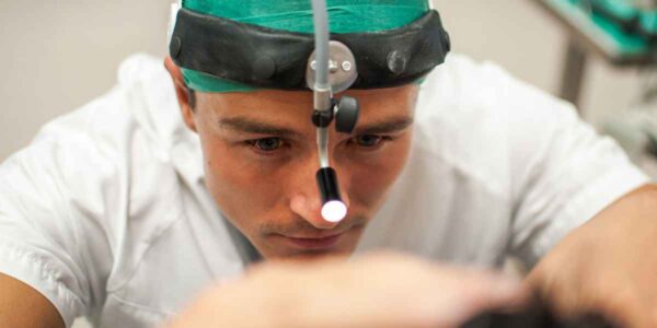A man dressed in a white shirt looks at a computer screen, reflecting deep focus and attention to detail.