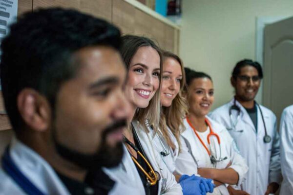 A group of smiling doctors stands together in a well-lit hallway, showcasing camaraderie and professionalism.