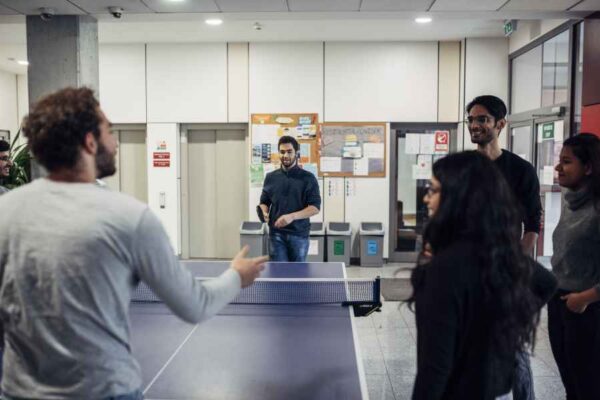 A group of colleagues enjoying a ping pong match in an office setting, promoting camaraderie and a fun work environment.