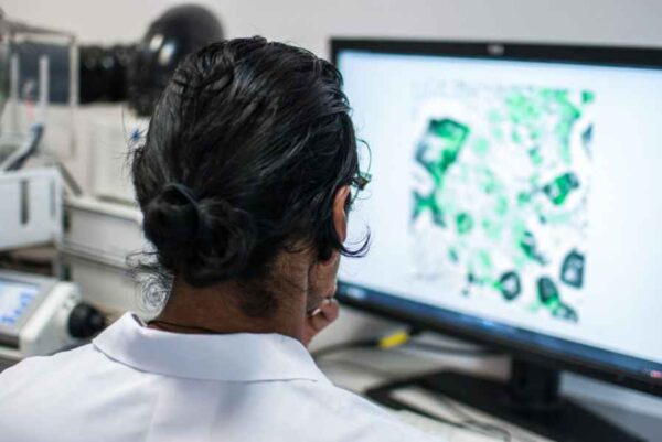 A scientist in a lab coat analyzes information displayed on a computer screen, reflecting her professional focus.
