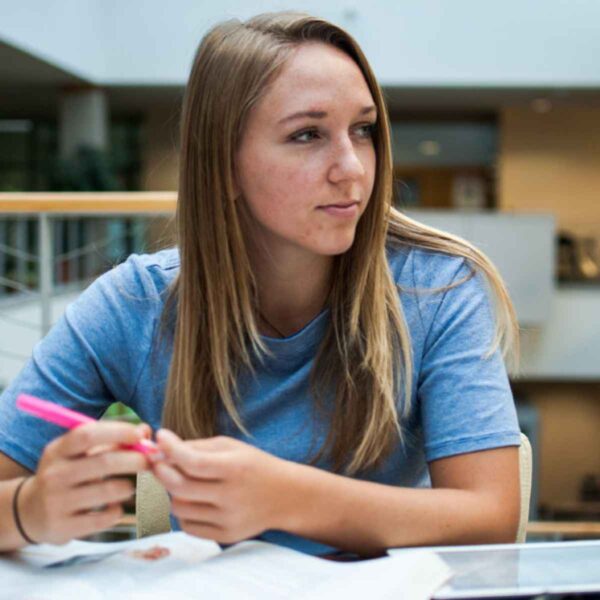 A young woman sitting at a table, intently working on her laptop, embodying a scene of modern digital engagement.