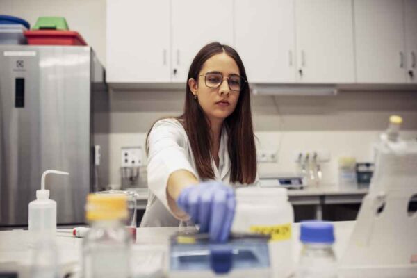 A student in a laboratory carefully organizing and preparing samples, focusing on precision while surrounded by scientific instruments.