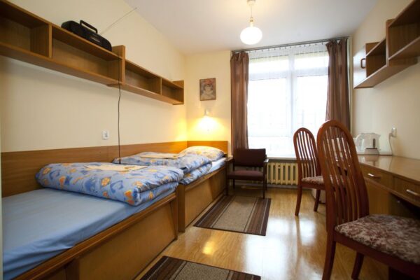 A small room featuring two beds and a desk, creating a cozy and functional living space for occupants.