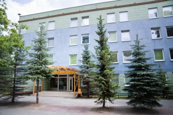 A building nestled among trees, showcasing a vibrant green door that adds charm to the landscape.