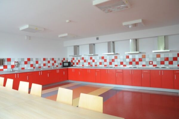 A modern kitchen featuring vibrant red cabinets and a central table, creating a warm and inviting atmosphere.